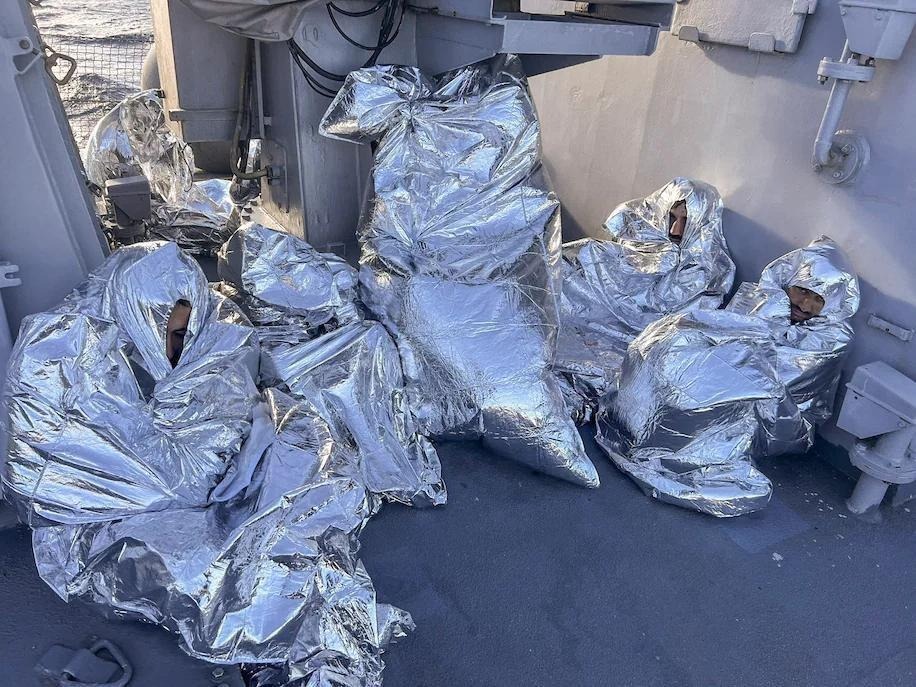 الصورة: مهاجرين مصريين نجوا من غرق قارب هجرة، مغطيين ببطانيات حرارية أثناء جلوسهم، وجثث مربوطة أيضا، على متن سفينة خفر السواحل اليونانية بعد العثور عليهم في جزيرة غير مأهولة، في بحر إيجة اليونان، 1 نوفمبر 2022. AP ©